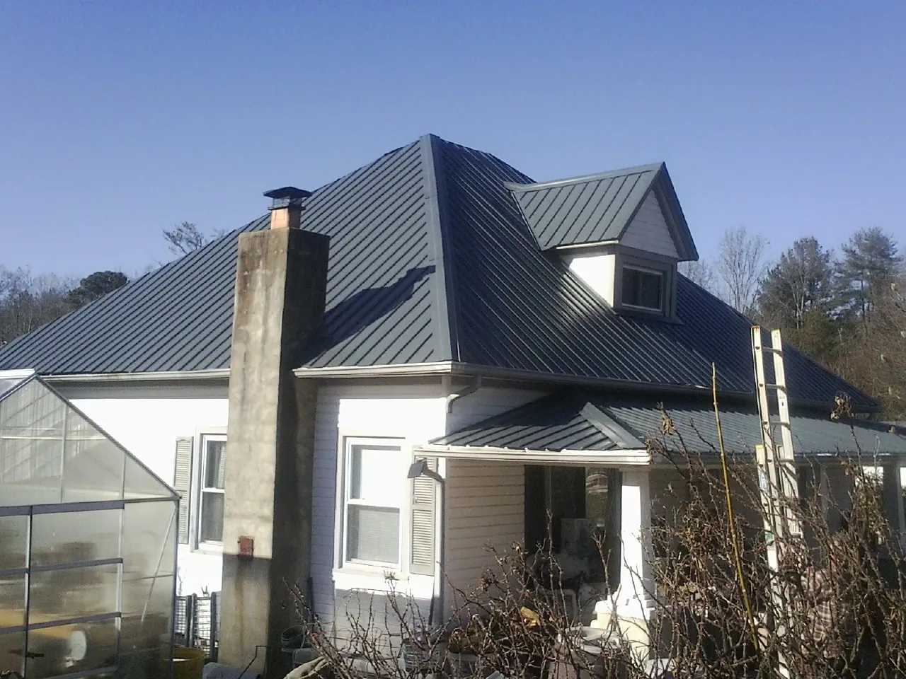 Dark blue standing seam metal roof on a white farmhouse with dormer — Slate & Tile Roof Repair by Roofing Brothers in State College