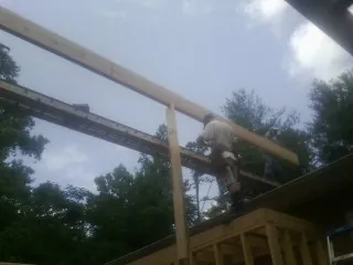 Carpenter setting a ridge beam over a new addition frame — Ice Dam Removal by Roofing Brothers in State College