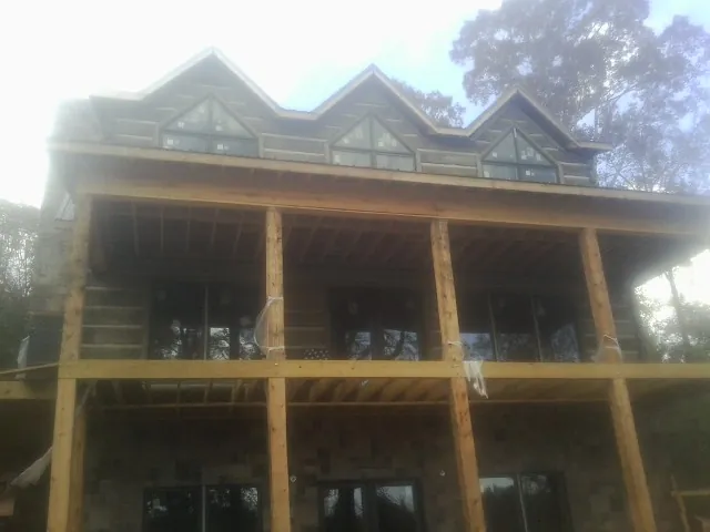 Dormers and porch framing on a large log home under construction — Roof Coating work by our crew in State College