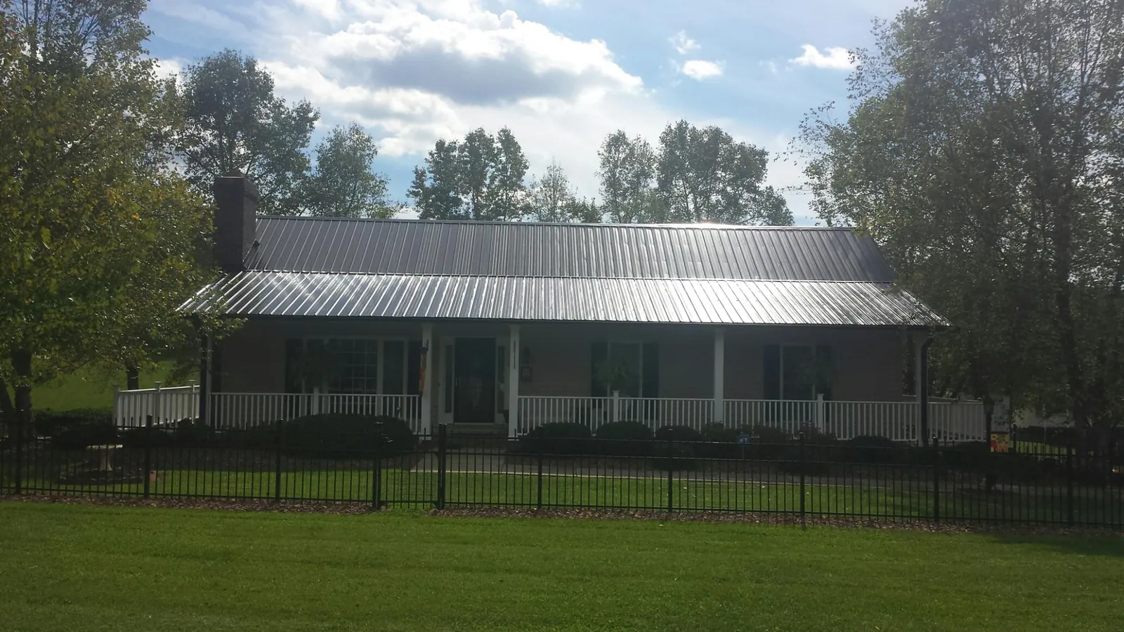Gray metal roof on a brick ranch with a full width front porch — Gutter Guard Installation work by our crew in State College