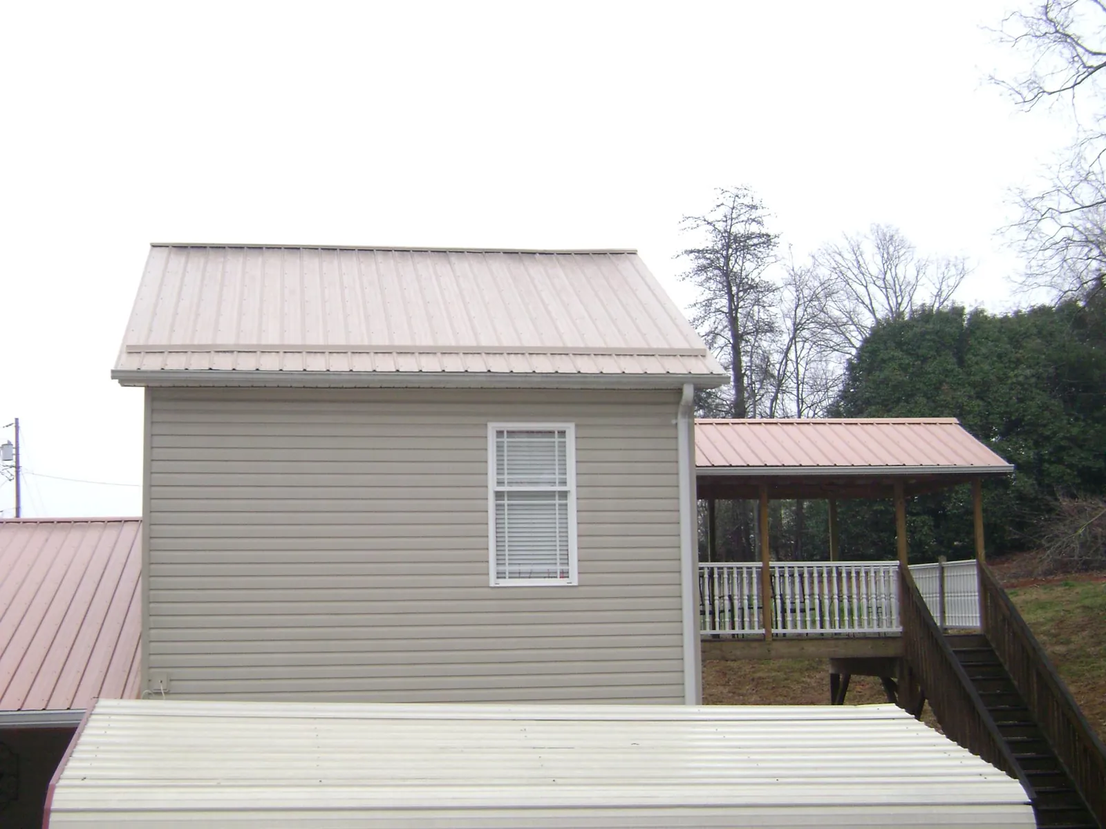 Tan metal roofs on a two story addition and attached porch, from a Roof Replacement job in State College