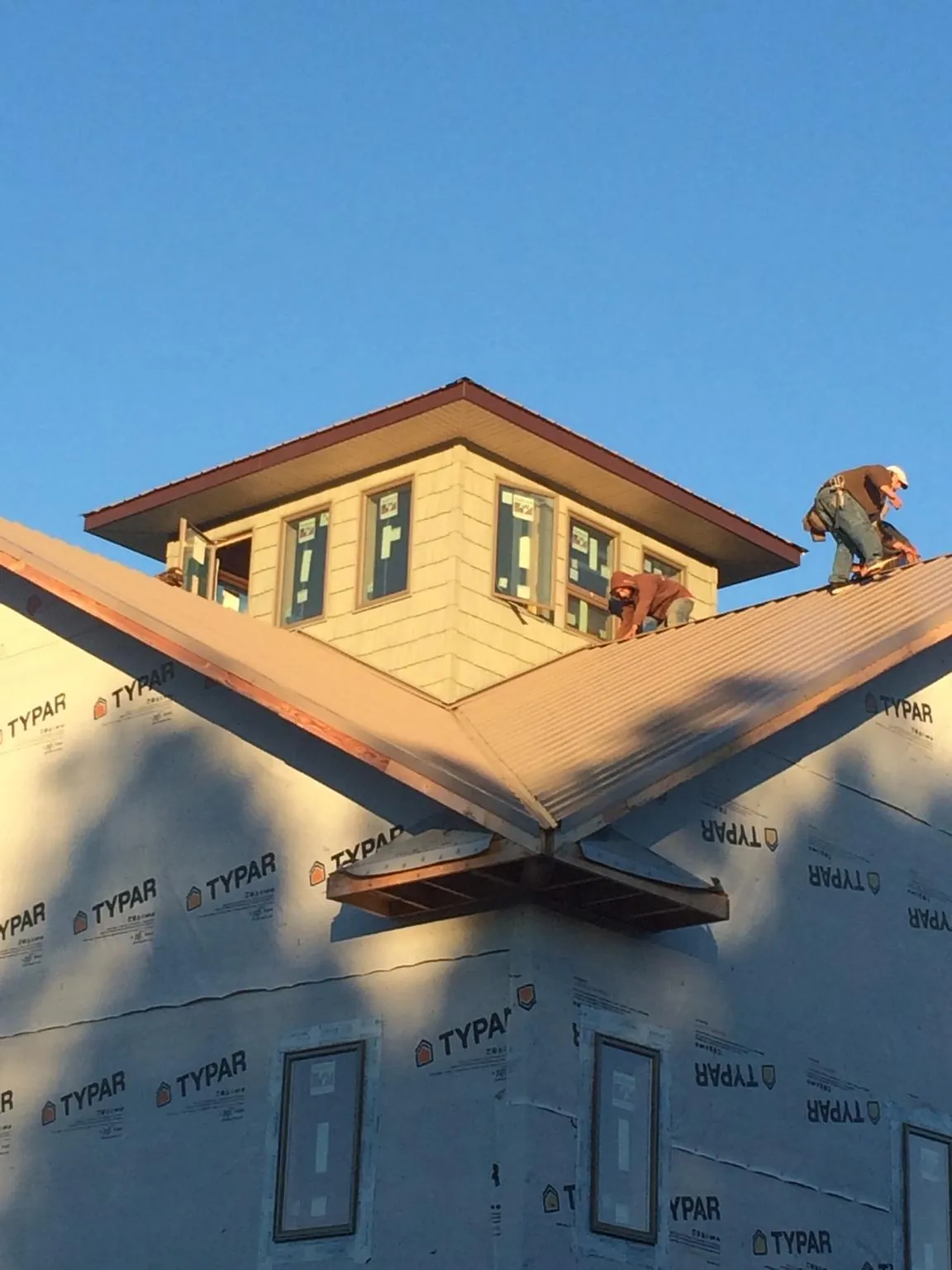 Roofers working around a rooftop cupola on a new metal roof at sunset — Roof Waterproofing in State College by Roofing Brothers